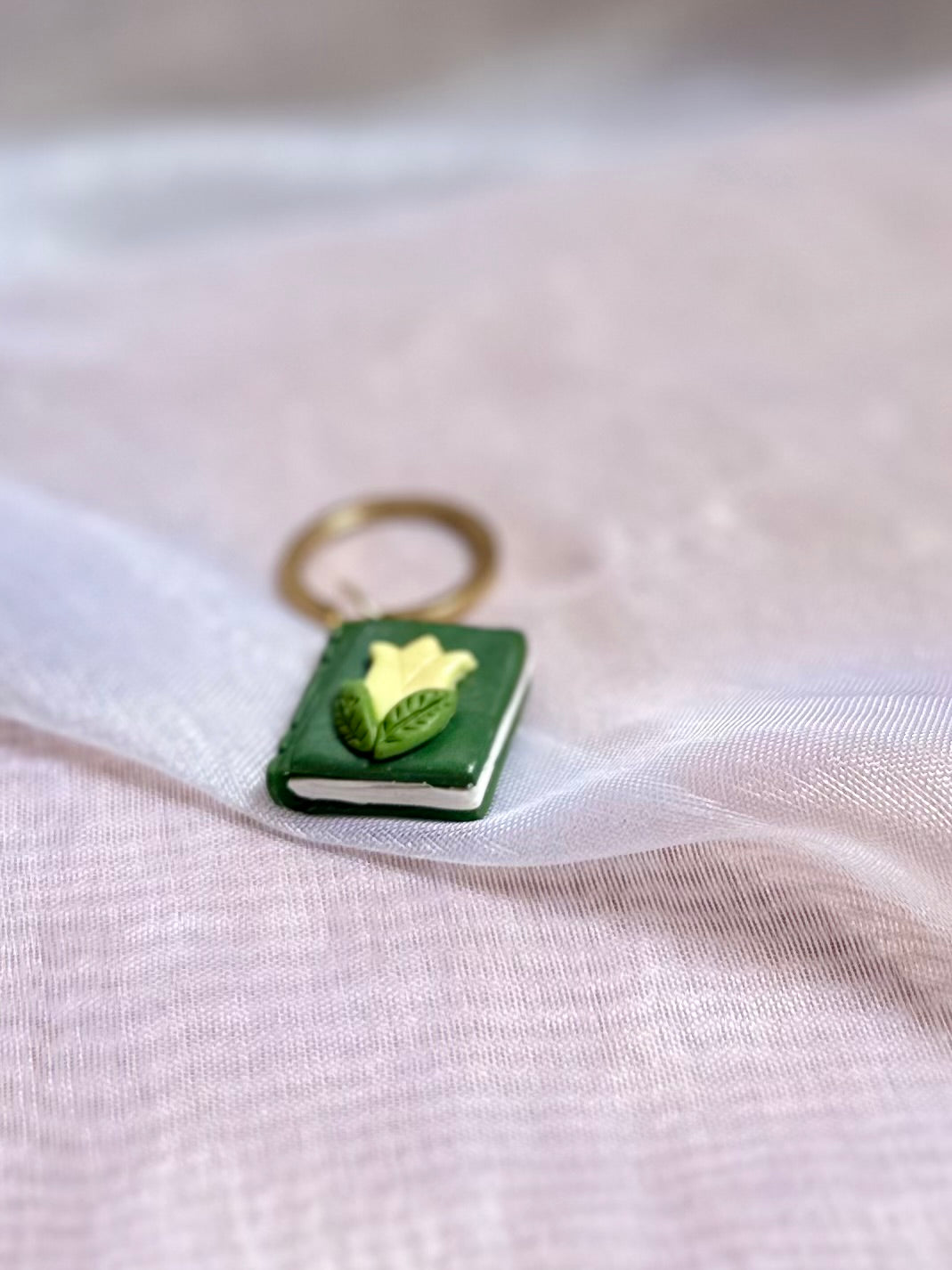 Llavero de libro verde y flor amarilla