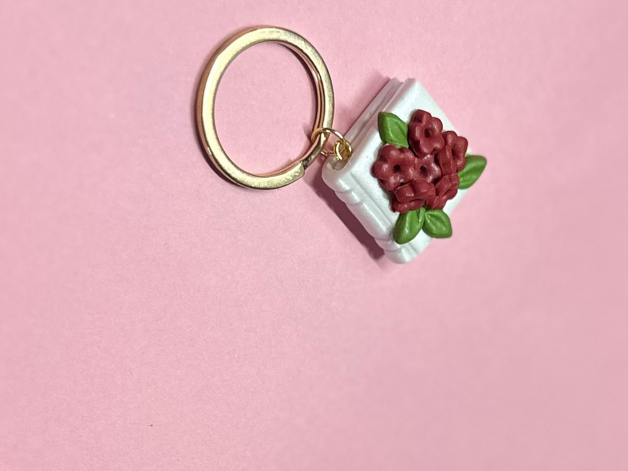 Llavero de libro blanco y flores rojas