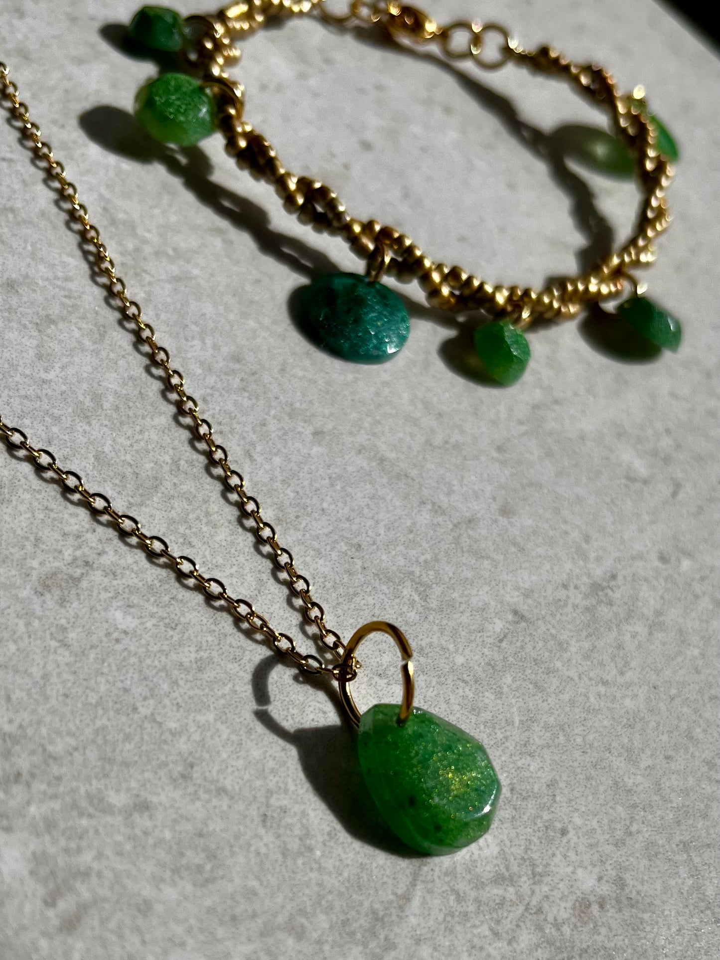 Conjunto de pendientes, collar y pulsera en dorado con accesorios de resina verde.