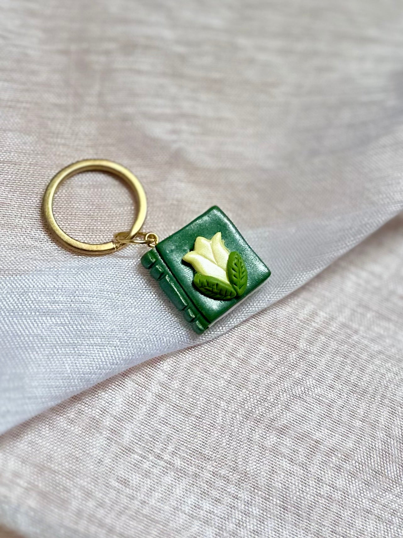 Llavero de libro verde y flor amarilla