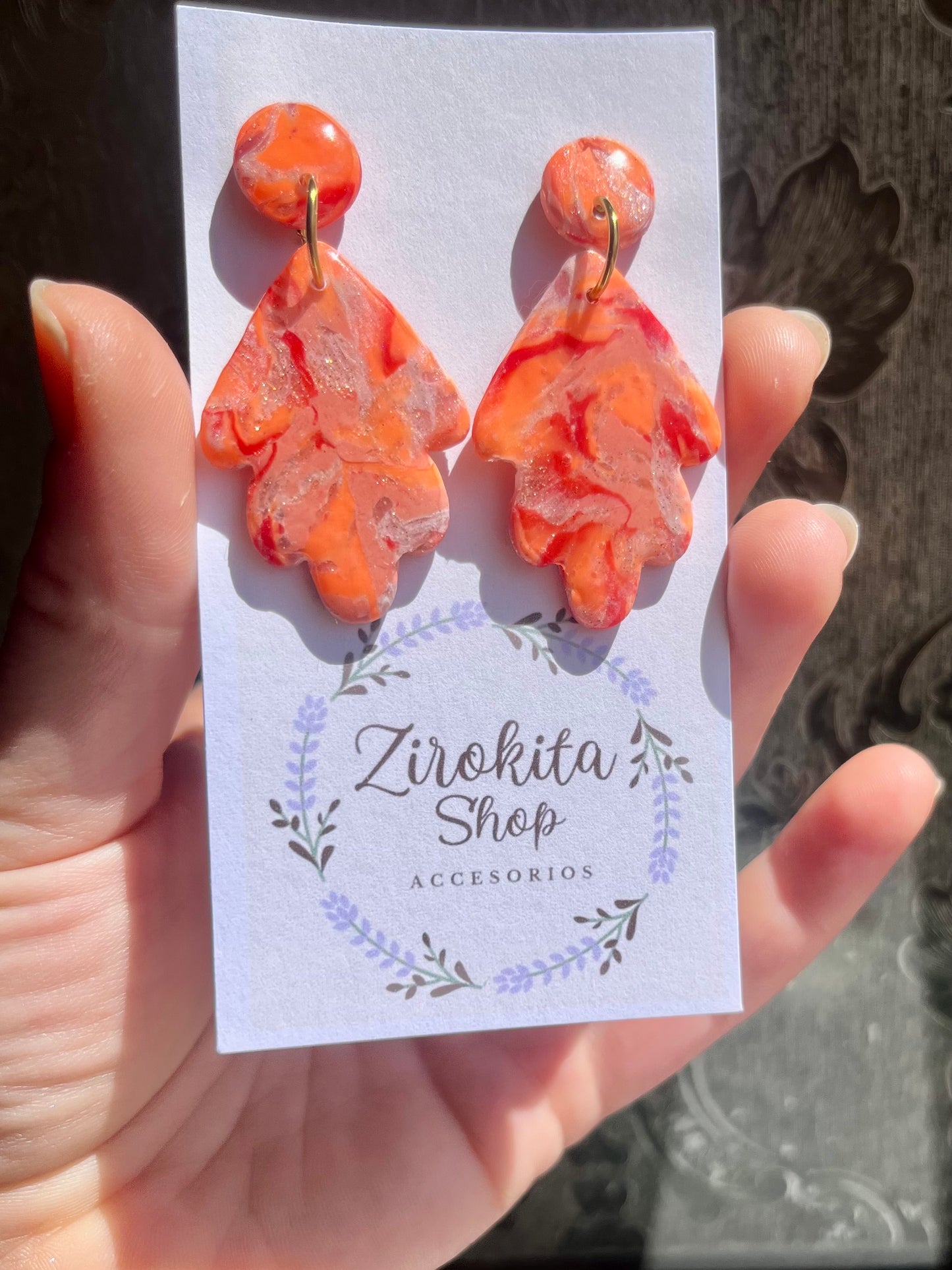 Pendientes de estampado en colores cálidos con accesorios en dorado.