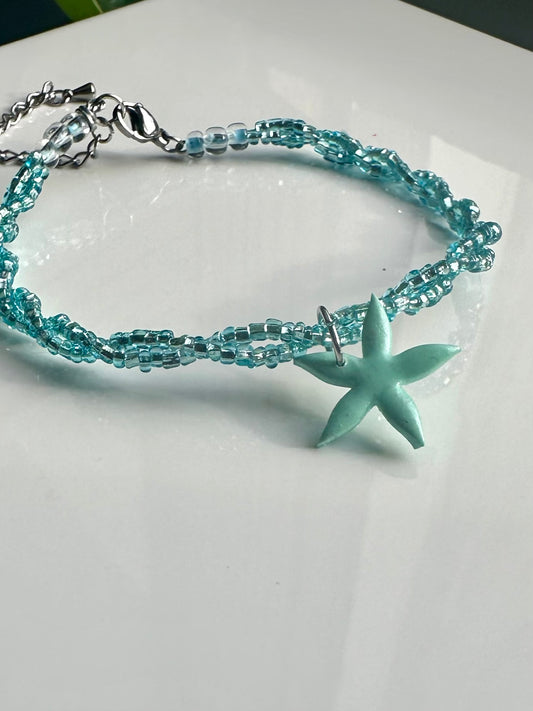 Pulsera de abalorios cruzados en azul y accesorio de estrella de arcilla polimerica.