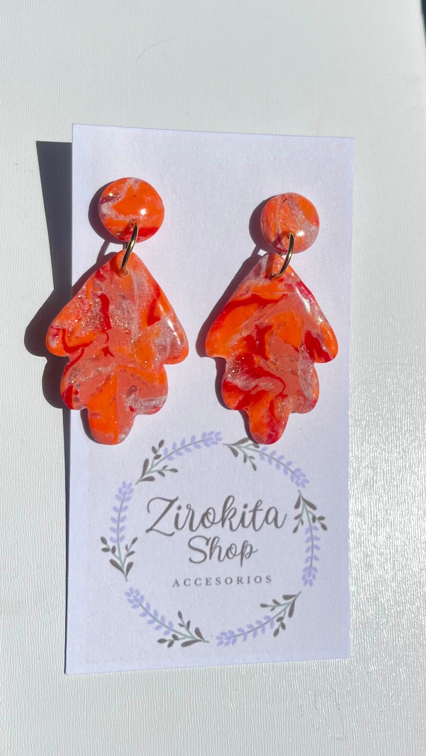 Pendientes de estampado en colores cálidos con accesorios en dorado.