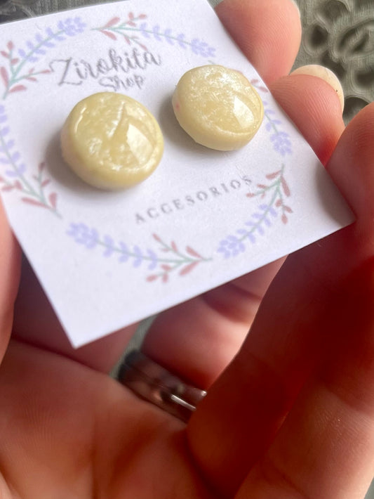 Pendientes circulares pequeños y brillantes con color amarillo vibrante.