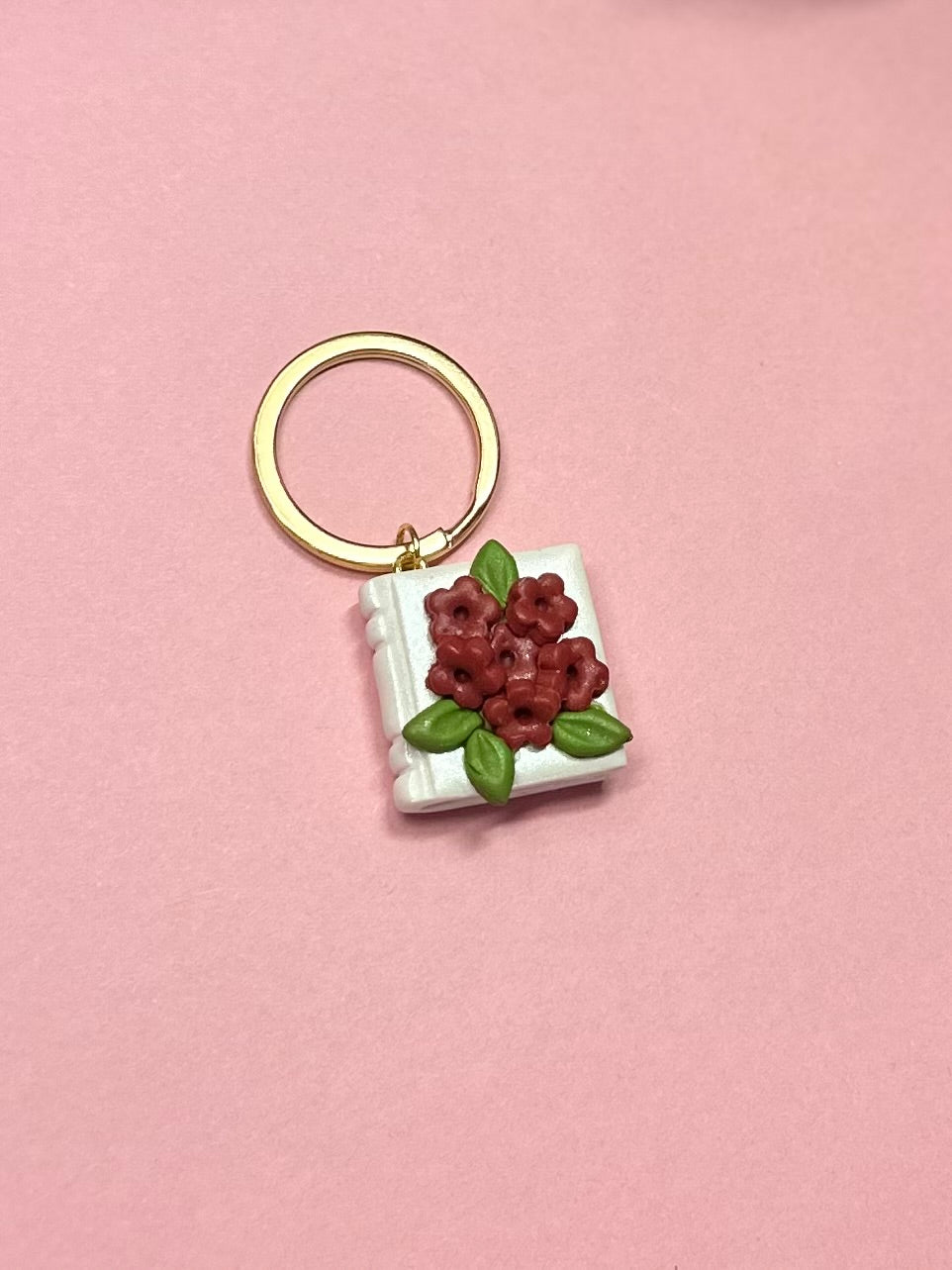 Llavero de libro blanco y flores rojas