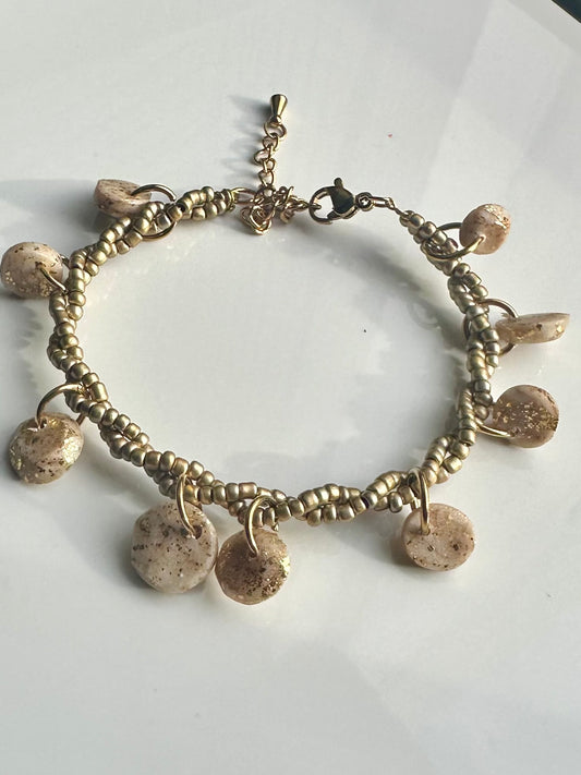 Pulsera de abalorios cruzados en dorado y accesorios de arcilla polimerica.