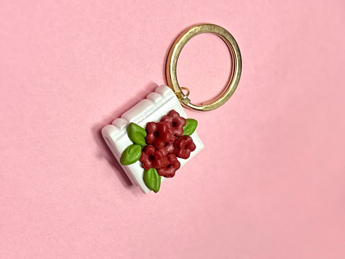 Llavero de libro blanco y flores rojas