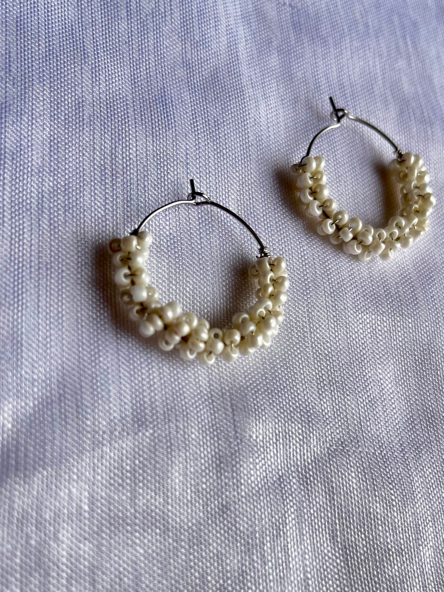 Aros plateados pequeños de abalorios blancos.