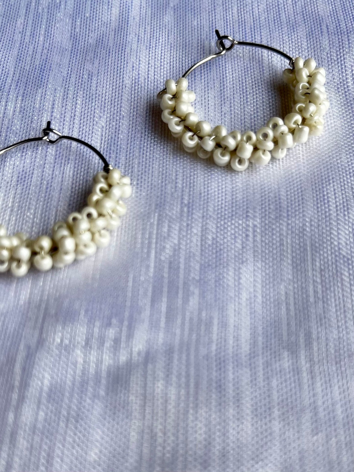 Aros plateados pequeños de abalorios blancos.
