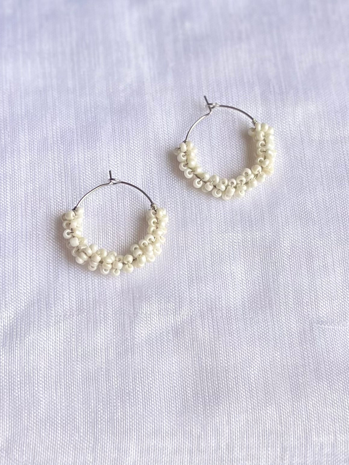 Aros plateados pequeños de abalorios blancos.