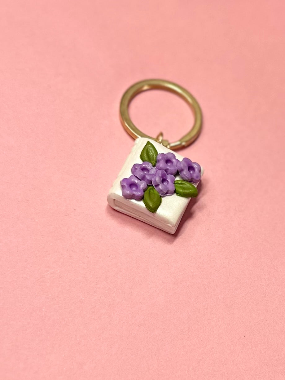 Llavero de libro blanco y flores lilas