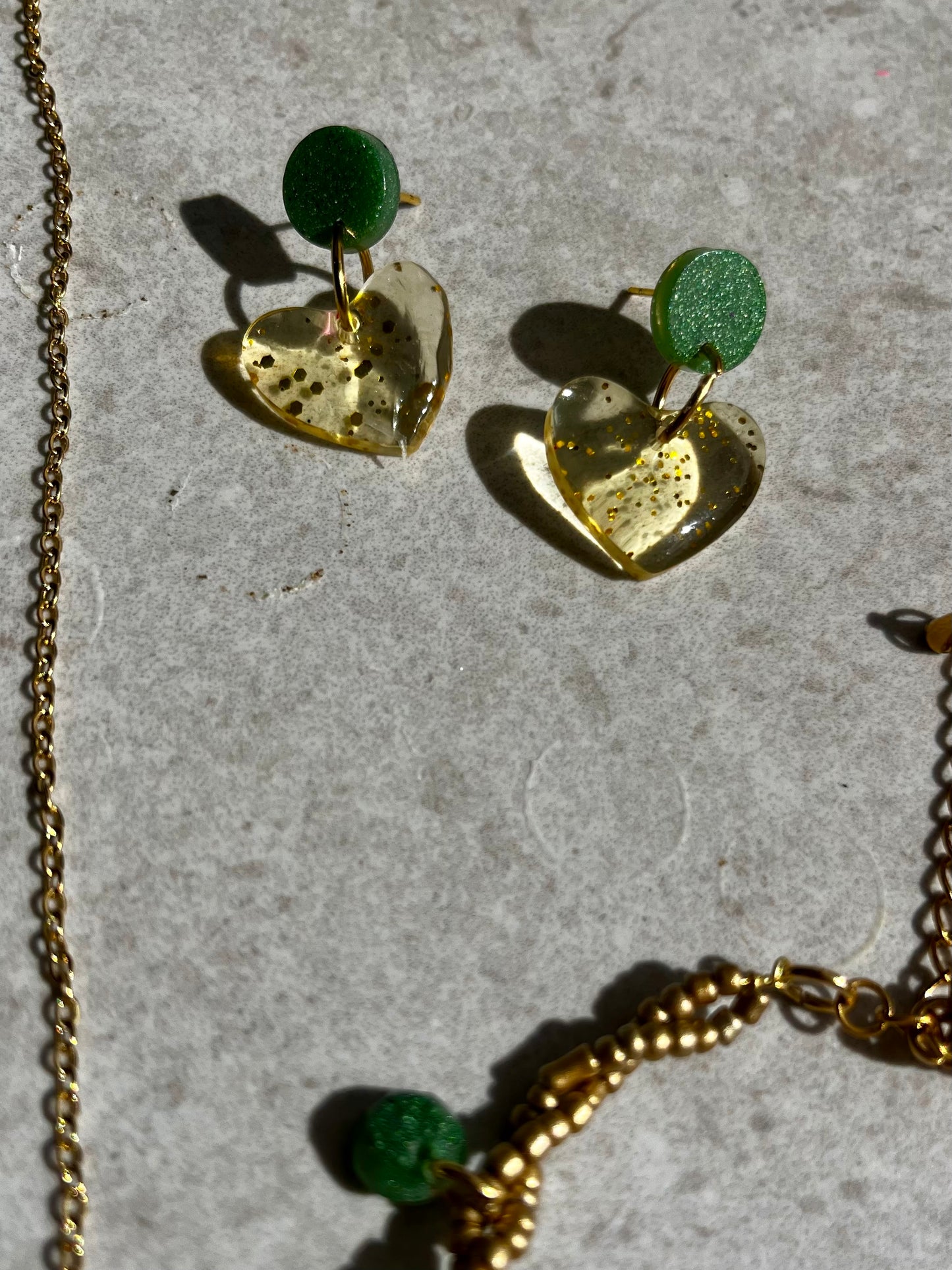 Conjunto de pendientes, collar y pulsera en dorado con accesorios de resina verde.