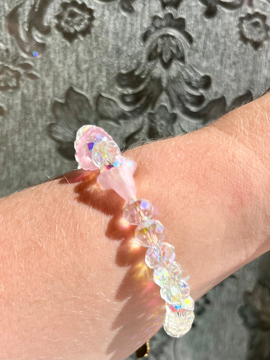 Pulsera elegante con piedras de cristal y flores rosas.