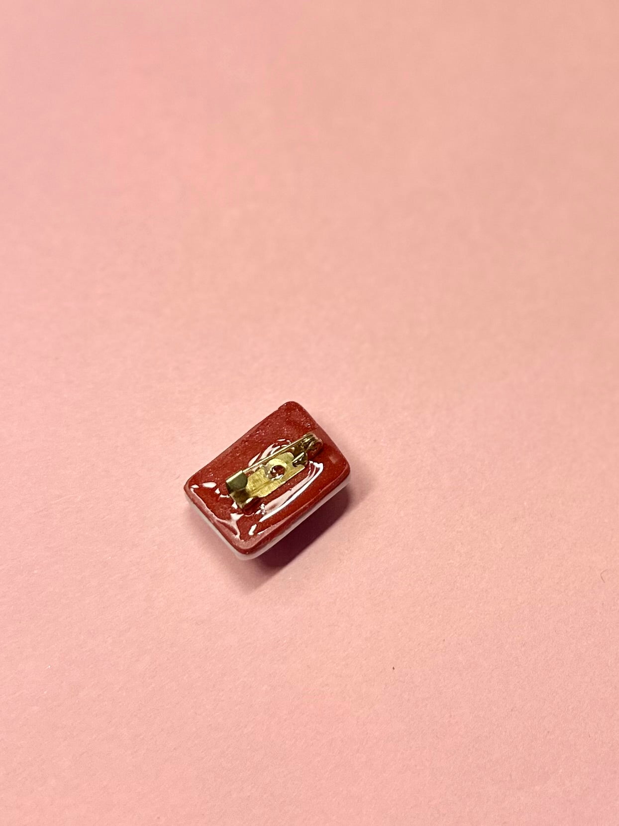 Broche de sobre blanco y flores rojas y lilas.